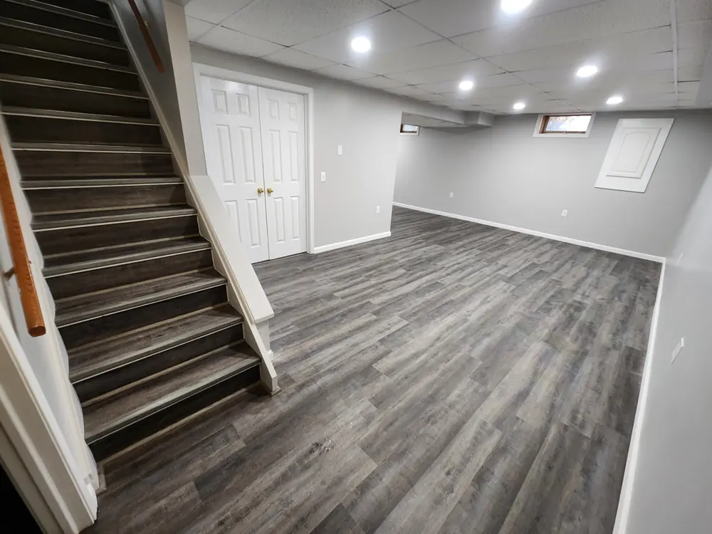 Finished basement with a wood stairway and continuous grey plank flooring