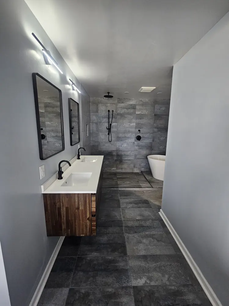 Remodeled bathroom with a floating double vanity, twin mirrors, a tiled walk-in shower and a freestanding tub