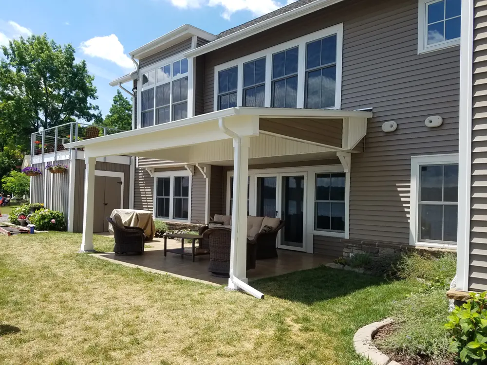 Covered patio with white posts and a finished ceiling along the back of a house