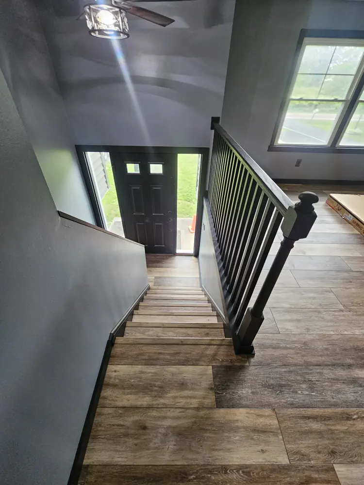 Interior entry with a black metal stair railing and wood-look plank flooring