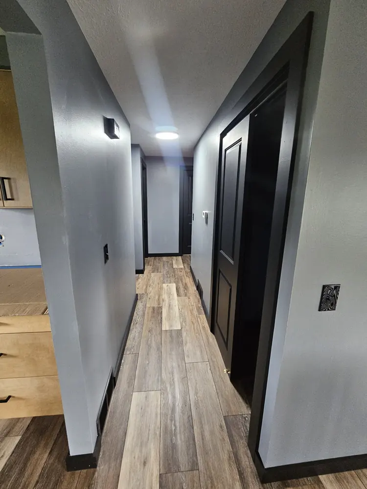 Renovated hallway with dark doors, grey walls and wood-look plank flooring