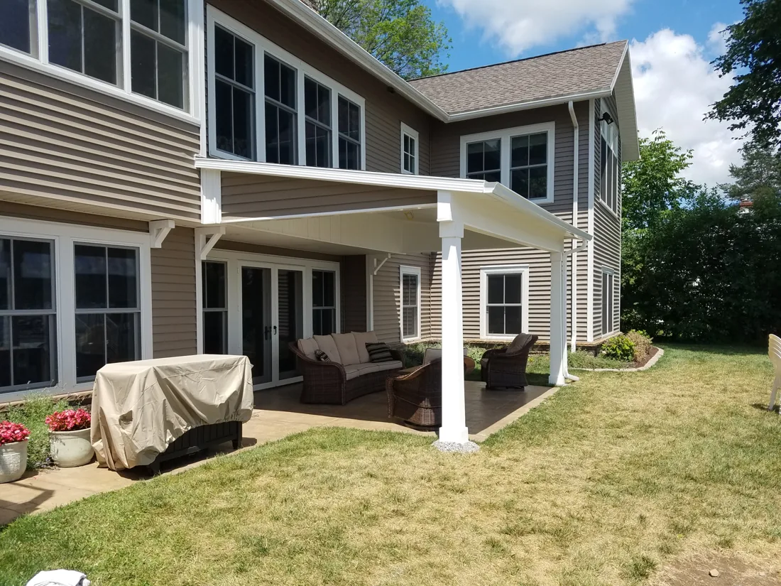 Covered patio with white posts and a finished ceiling, built along the back of a house
