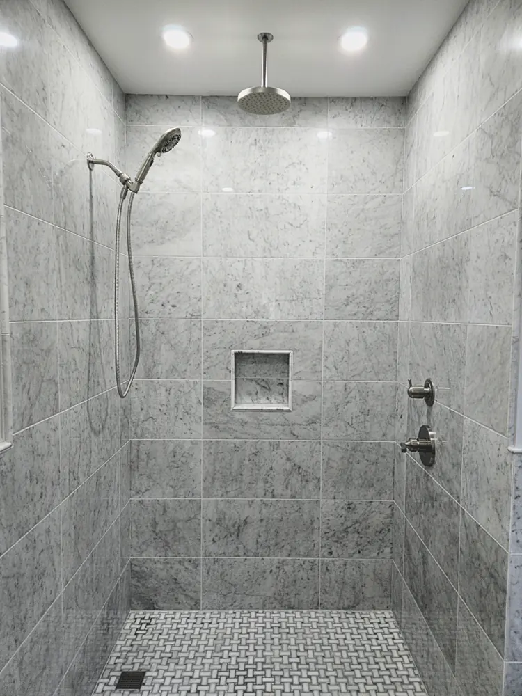 Grey marble-look tiled shower wall with a recessed niche and a handheld fixture