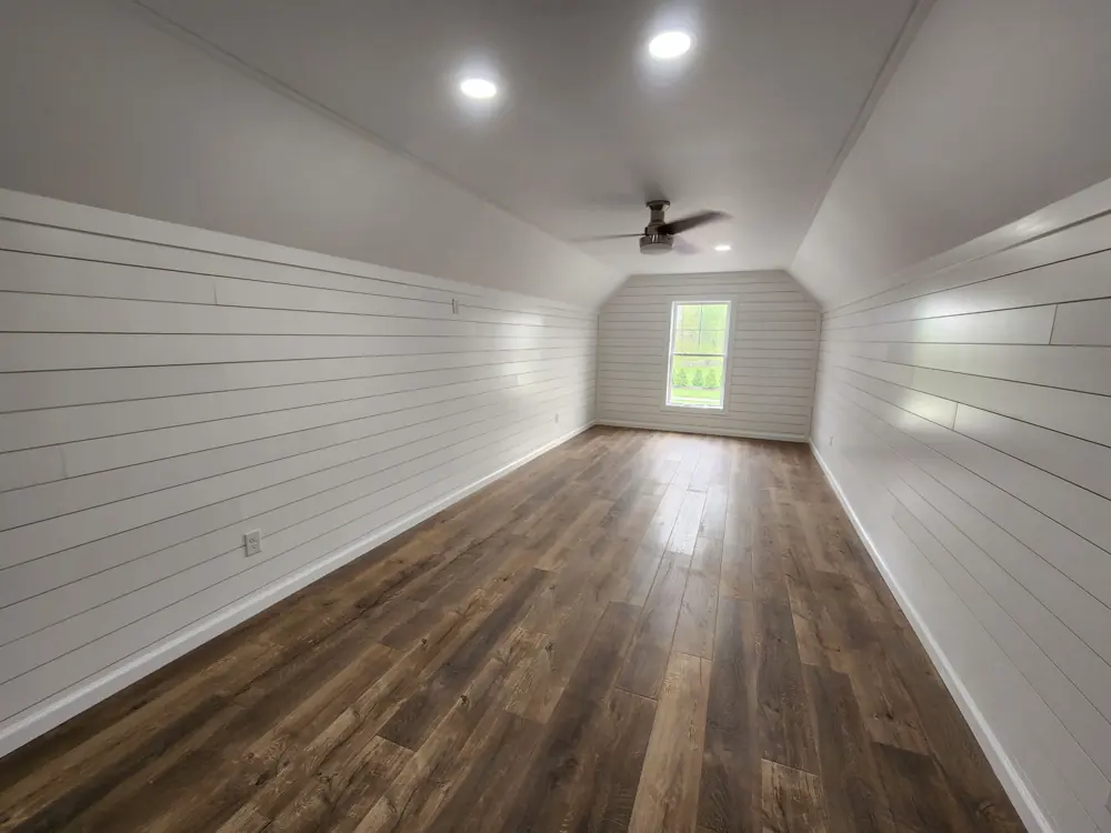 Room with white panelled walls, recessed lighting and a wood floor