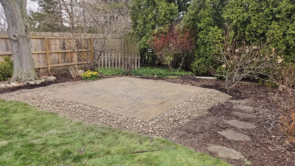Paver patio laid in a back garden with a gravel border