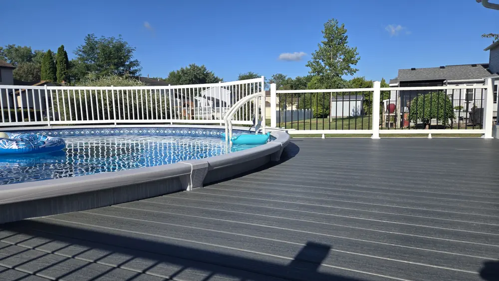 Composite deck with black aluminium railing wrapping an above-ground pool