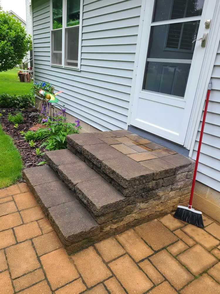 Stone slab steps set into a paver landing beside a house
